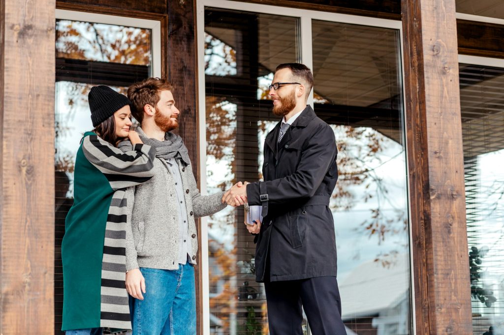 Young couple with real estate agent near house, real estate purchase